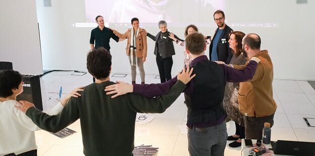 A group of people standing in a circle with their hands on each other's shoulders.
