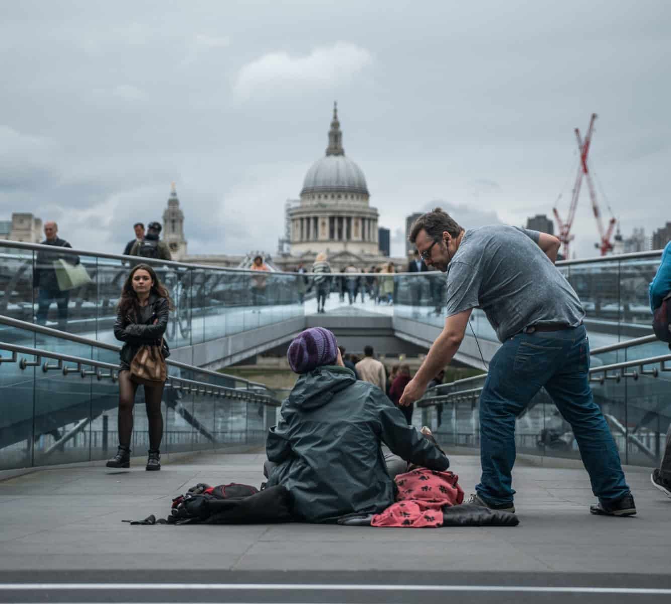 Man giving change to beggar with backdrop of St Paul's Cathedral in London
